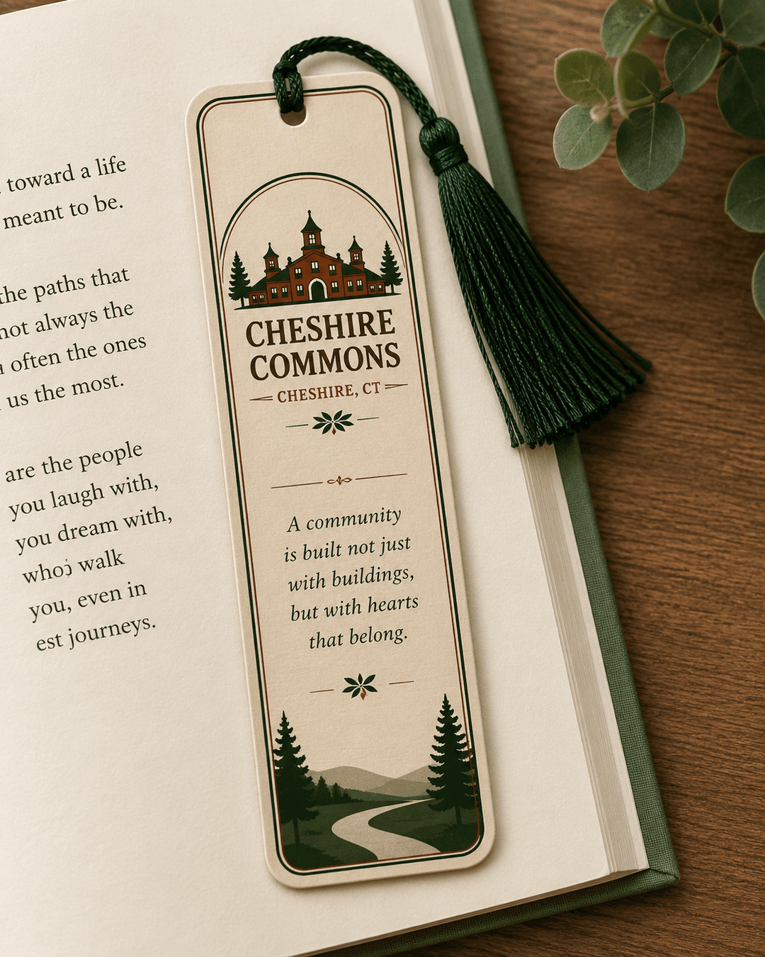 Ivory tasseled bookmark with the Cheshire Commons crest, resting in an open book