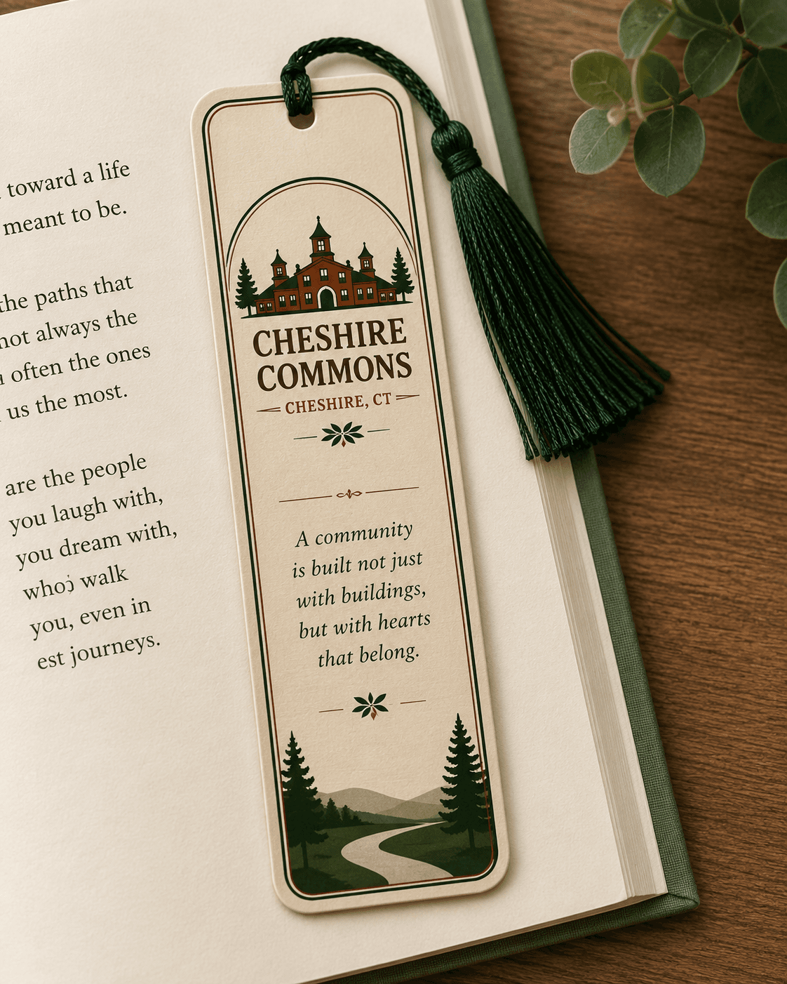 Ivory tasseled bookmark with the Cheshire Commons crest, resting in an open book