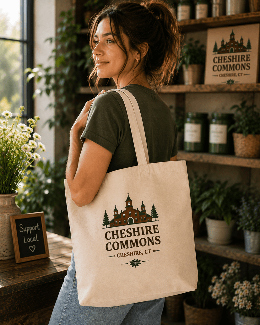 Model carrying an ivory canvas tote bag printed with the Cheshire Commons crest